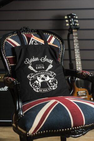 Gordon Smith tote bag with the iconic GS crossed guitars tattoo - portrait - sitting on chair - 2